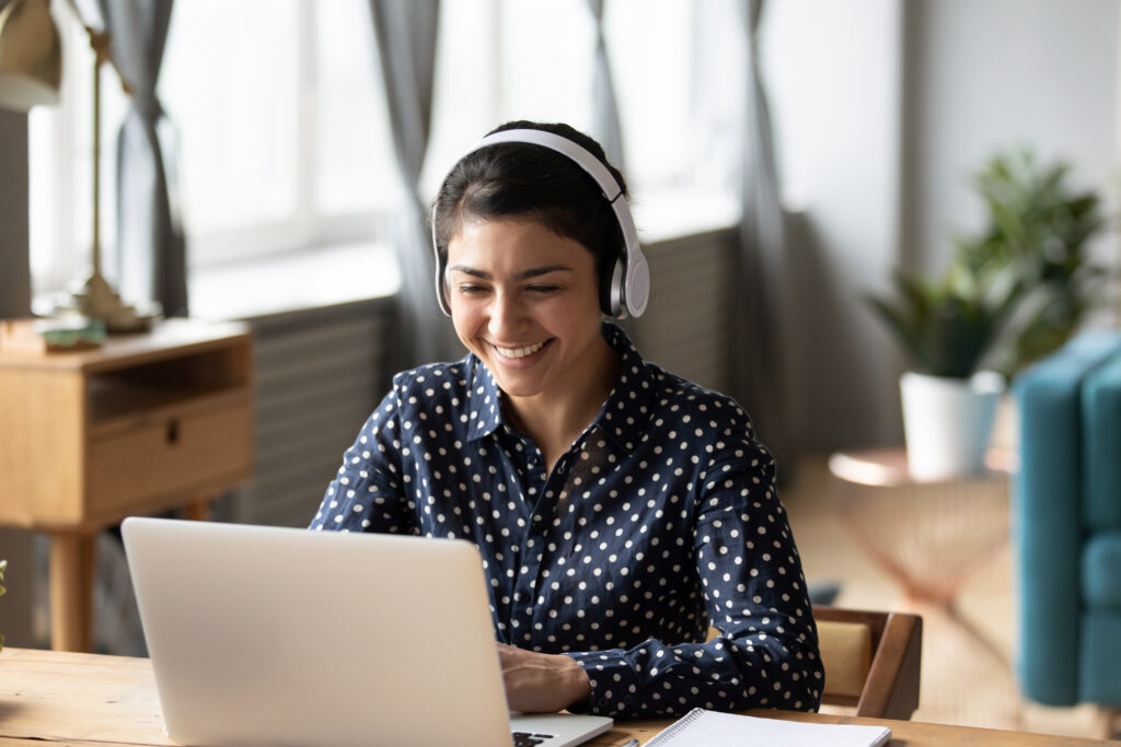 Woman wearing headphones working on a laptop from home